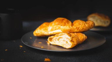 Koyu arkaplanda kahve olan kruvasan.