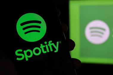 Bandung, Endonezya - 4 Ocak 2025: Bu resimde Spotify logosu arkaplanda Spotify Musik logosu bulunan bir akıllı telefonda sergileniyor.