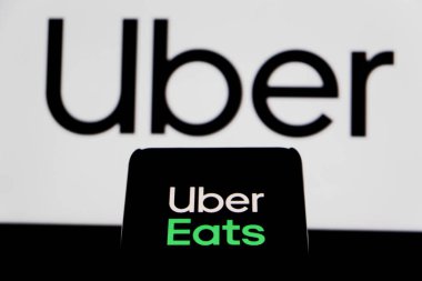 Bandung, Indonesia - August 13, 2025: In this photo illustration, a person holds a smartphone showing The Uber logo is displayed on a mobile phone with Uber in the background.