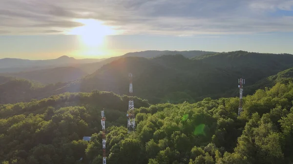 stock image Aerial view of 5G telecommunication towers standing tall on dense green mountains against beautiful sunlight