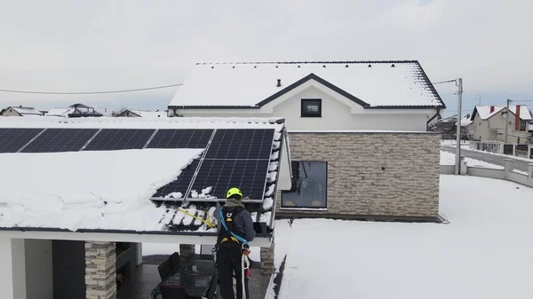 Technician engineer working on power outage blackout on solar panel during a winter snowstorm. Modern smart house covered in snow