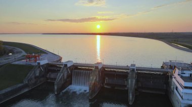 Hydroelectric dam power plant station production of energy supply for city life. Aerial view during colorful sunset big lake natural unpolluted landscape clipart