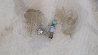 Yükleyicinin ezilmiş taşı kamyona yüklediği tepeden aşağı hava görüntüsü