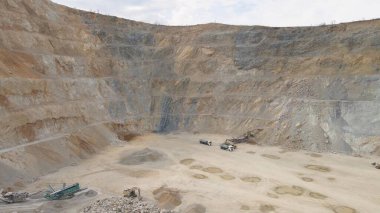 İHA atışı büyük bir taş ocağının önünden yükseliyor. Makineler çalışıyor, bulutlu bir gün.