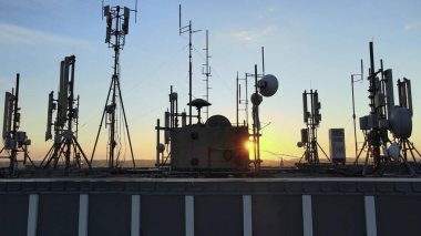 Altın saat boyunca çatıdaki anten, mikrodalga ve panel antenli elektromanyetik kulelerin silueti