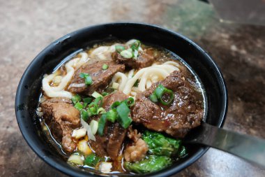 Tayvan yemeğinin üst manzarasında bir kasede servis edilen etli şehriye sosu. Tahta masadaki kasede etli şehriye çorbası. Çin Tayvan mutfağı