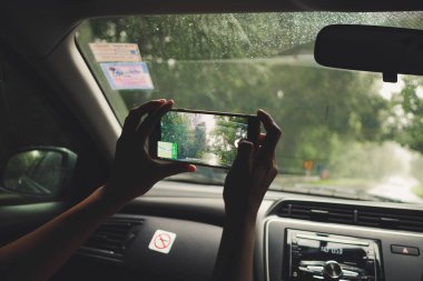 Kadınlar, bulanık arabanın arka planında navigasyon uygulaması ya da GPS kullanıyorlar. Kadınlar video yolculukları sırasında ekranlarında konum haritası olan bir cep telefonu tutuyorlar..
