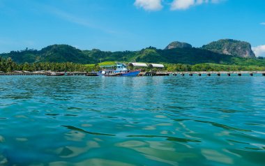 Güzel mavi gökyüzü ve beyaz bulutları olan tropikal sahildeki iskele köprüsü. Deniz manzarası ya da plaj geçmişi. MooK Adası, Tayland