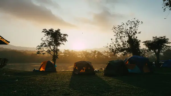 Camping and tent near lake in sunrise. Beautiful sunset on the lake. There is a tent nearby. Silhouette