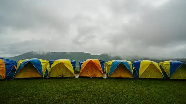 Tourist tent with the spectacular view of Khao Kho, Phetchabun Province in Thailand. Tent in camping with flog and mountain view. Tent on campsite by the hill in rainy day.