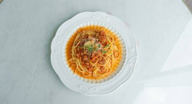 Beyaz arka planda domates soslu spagetti. Domates soslu spagetti ile beyaz tabağın üst görüntüsü. Beyaz tabakta pembe arka planda spagetti bolonez. Bolonez sosu klasik İtalyan mutfağıdır. Popüler İtalyan yemekleri..