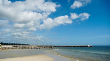 Güzel mavi gökyüzü ve beyaz bulutları olan tropikal sahildeki iskele köprüsü. Deniz manzarası ya da plaj geçmişi. HuaHin, Tayland