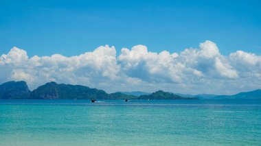 Tropik bir manzara. Turkuaz okyanus suyuyla beyaz bulutlu mavi gökyüzüne ve tropikal adaya karşı. Yaz tatili için doğal manzara, panoramik manzara. Koh Kradan, Tayland.