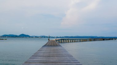 Ahşap köprü sessiz bir plajın kenarında oturur ve sakin deniz suyunun güzel bir manzarasına sahiptir. Yanaşma gemisine giden yol olarak tahta köprü. Asgari deniz havası, sakin su yüzeyi ve yansımaları.