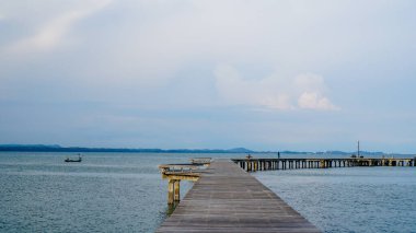 Ahşap köprü sessiz bir plajın kenarında oturur ve sakin deniz suyunun güzel bir manzarasına sahiptir. Yanaşma gemisine giden yol olarak tahta köprü. Asgari deniz havası, sakin su yüzeyi ve yansımaları.