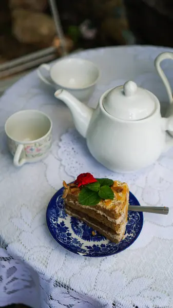 Delicious cake and hot tea on table in the garden ,relax time. Bed set for afternoon tea with white tea set. Tea party.