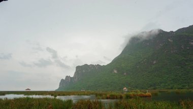 Tatlı su bataklığının ortasında ahşap yürüyüş yolu ve pavyon, mavi gökyüzü, bulutlu ve yasaklama işaretleri. Sam Roi Yot Tatlı Su Bataklığı veya Bueng Bua Khao Sam Roi Yot Ulusal Parkı Tayland.