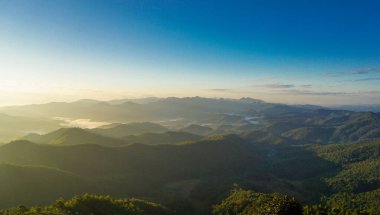 İnanılmaz doğa manzarası, sabah sisinin altındaki dağlar gün doğumunda. Turistlerin seyahat günlerinde, kış atmosferinin geri planına başlayan bir manzara manzarası, dağ ve sis veya sis. Dağın üstünde güzel bir gün doğumu