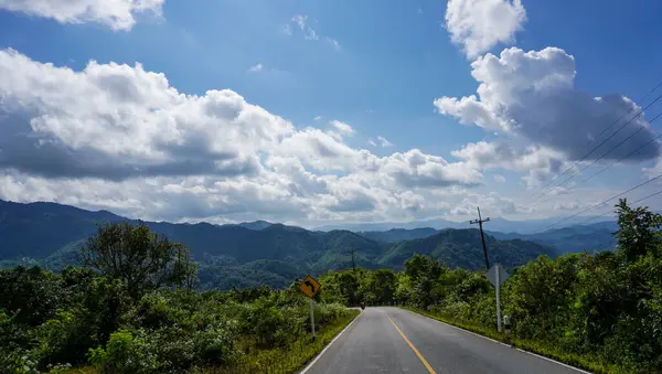 Country road shows the curves of the line road alongside the abundant tropical forest in the north part of Thailand. Scenic Nature of Mountain. Take pictures while the car is running, Two-sided Landscape Roads.