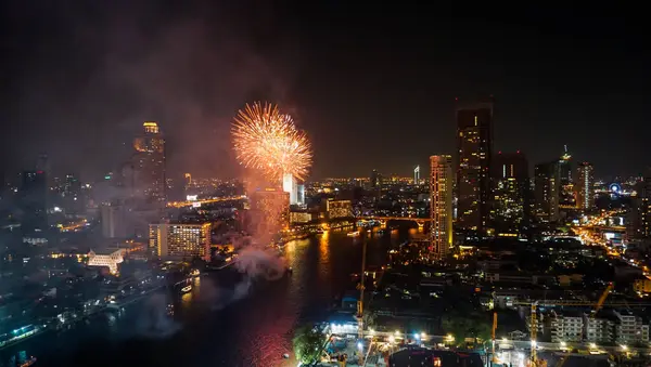 Firework lighting in Bangkok cityscape background, Night view and firework. Celebration fireworks exploding of New year's day or Christmas celebration day in downtown district at Chao Phraya River, Thailand.