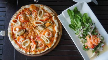 Orjinal İtalyan deniz ürünleri pizzası ahşap tabakta dilimlenmiş. Taze çiğ somon balığı, deniz mahsulü somon balığı, somon salatası, somon balığı, sebze salatası ve baharat ile birlikte somon filetosu..