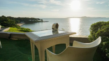 Deniz kenarında romantik bir masa ve güzel bir günbatımı gökyüzü. Deniz kıyısında bir restoranın masası..