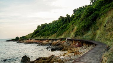 Tayland 'da gökyüzüne karşı deniz manzarası. Güzel bir sahil manzarası. Sahildeki Rocky Sahili. Güzel deniz manzaralı ahşap köprü. Büyük kayalık sahil şeridinde tahta köprü manzarası açık turkuaz deniz üzerinde kaya önü