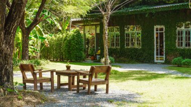 Yeşillik arka bahçedeki çimenlikte boyalı iki sandalye. Tahta sandalye ve bahçede bir masa. Rahatlamak ve dinlenmek için bir yer Yaz bahçesinde.