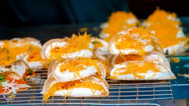 Khanom Bueng. Şekerle karıştırılmış yumurta beyazından yapılmış beyaz krema krema gibi pürüzsüz olana kadar dövülmüş. Foi tangalı garnitür ya da kızarmış karides, geleneksel Tayland tatlısı. Popüler atıştırmalıklar