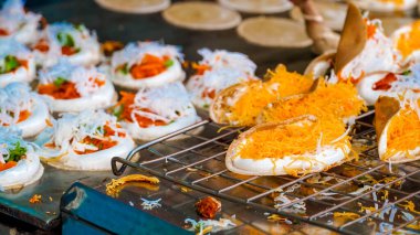 Khanom Bueng. Şekerle karıştırılmış yumurta beyazından yapılmış beyaz krema krema gibi pürüzsüz olana kadar dövülmüş. Foi tangalı garnitür ya da kızarmış karides, geleneksel Tayland tatlısı. Popüler atıştırmalıklar