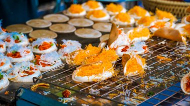 Khanom Bueng. Şekerle karıştırılmış yumurta beyazından yapılmış beyaz krema krema gibi pürüzsüz olana kadar dövülmüş. Foi tangalı garnitür ya da kızarmış karides, geleneksel Tayland tatlısı. Popüler atıştırmalıklar