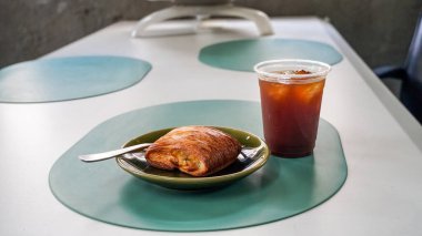 Kahvaltı manzarası bir sürü çikolatalı kruvasan ve kafenin arka planında bir fincan kahve. Restoran menüleri için mükemmel. Yumuşak ışıklar, rahat ve rahatlatıcı bir atmosfer yaratır.