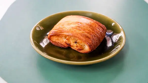 Freshly baked sweet buns puff pastry with chocolate and croissants. Pain au chocolate on a plate on a outdoor cafe table. a pain au chocolate, its flaky layers glistening with a sheen of melted chocolate, sweet filling