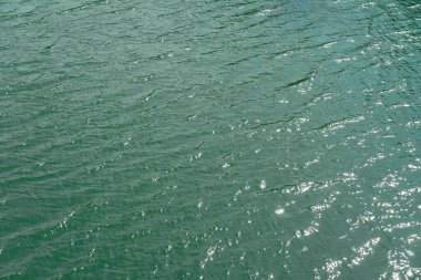 Yukarıdan nehir, okyanus suyu yüzeyi anten görüntüsü, su dokusu arka plan, göl dalgaları üzerindeki açık mavi yansıma düz yüzey. Güneş ışığı yansıtıyor ya da suyun üzerinde parıldıyor.