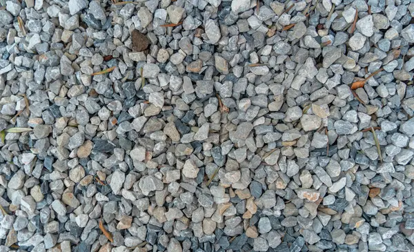 Gravel outdoor road. Closeup gravel texture. Stone pattern. Small rocks ground. Crushed rock. Gray gravel floor texture and background.