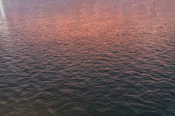 Texture of the water surface, sunset light. Morning sea close-up view romantic beautiful background. Detailed close up view on water surfaces with waves and ripples and the sunset sunlight reflecting at the surface.