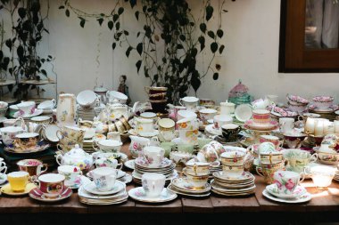 Bir sürü yeni çay fincanı ve çay tabağı dizayn edildi. Çiçekli çay fincanları koleksiyonu. Dolapta bir sürü farklı çaydanlık var. Kadife perdelerin arka planında doğu tarzında çay seti.