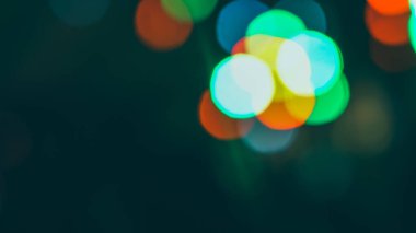 Parlak arkaplan ışığıyla parlayan ışıltılarla odaklanmış soyut bir arka plan. Soyut çok renkli ışıklar. Renkli bokeh, parlak bulanık Noel ışıkları. Siyah arka planda bulanık ve parlayan ışıklar. Odaklanmamış neon ışığı.