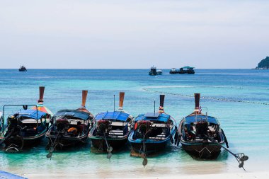 Uzun kuyruklu tekne Lipe Adası, Tayland 'daki cennet adası. Gökyüzüne Karşı Sahilde Uzun Kuyruklu Tekneler 'in Manzarası. Göz kamaştırıcı yaz manzarası. Andaman Denizi 'nde uzun bir balıkçı teknesi grubu. Geleneksel Tekne Kristal Temiz Su.