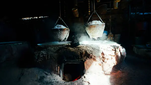 Selective Salt In Basket Is Hungover Stove Is Product Of Salty Water From Underground In Mountains,Nan ,Thailand. Boiling rock salt, traditional salt making. Rock salt is in a basket hanging above a pan for boiling brine is placed in a salt producing