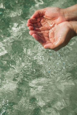 Saf suyla birlikte eller. Suyu dolu ellerle tutmak. Göl suyuna dokunan bir kadının eli. Bir insanın eli dalgalı bir su yüzeyine dokunmak için uzanır, duyusal algının dokunsal boyutunu keşfeder. Arınma kavramları, n