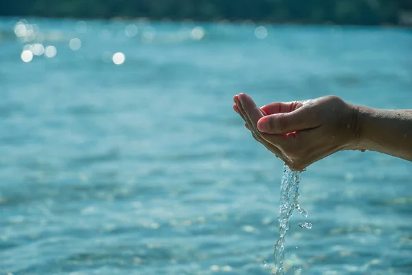 Hands with pure water. Holding water in cupped hands. Closeup of a woman\'s hand touching the lake water. A person\'s hand reaching out to touch a rippling water surface, exploring the tactile dimension of sensory perception. A concepts of cleansing, n