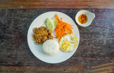 Kızarmış Tayland yemeği sarımsaklı ve Tayland biberli kızarmış sarımsaklı pirinç, kızarmış yumurta ve domates oymalı beyaz tabak manzaralı..