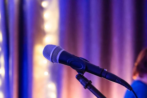 Microphone on stage. microphone on stand with colorful light bokeh background in conference hall. Close up of microphone on stage in audience room blur background.