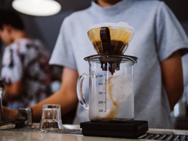 Damlatma filtresi kahvesi demleniyor. Barista sıcak suyu hunide öğütülmüş kahveyle filtreden aşağı döküyor. Alternatif su dökme metodunu filtrede bulunan kahve çekirdeklerinin üzerine dökün.