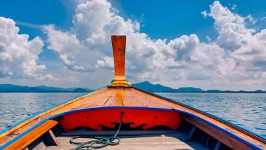 Tayland 'da gemi burun manzaralı uzun kuyruk teknesi. Dekorasyon çiçekleri ve kurdeleleri olan geleneksel bir kuyruk teknesi. Beyaz bulut ve açık gökyüzü.