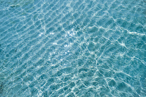 Blue ripped sea water as swimming pool Crystal clear ocean lagoon bay turquoise blue azure water surface closeup natural. close up of water of the ocean with sun shine sparkling.