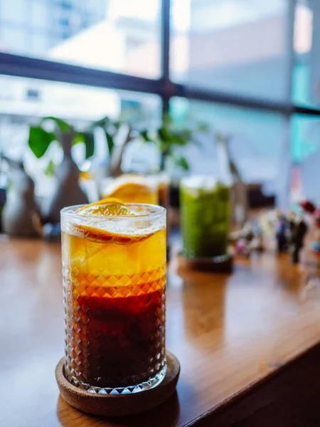 A Glass of bumble cocktail with ice. Double espresso with orange juice and caramel syrup with orange juice with orange slices on the glass. Fresh and sweet cold summer drink. Trendy iced coffee.