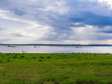 Göl üzerinde dramatik fırtına bulutları sağanak yağış ve fırtınayı delip geçen ruhani ışık ışınları yağmurdan önceki gökyüzü. Suyun üzerinde fırtına bulutları. Tayland 'da gölün üzerinde fırtına bulutları.