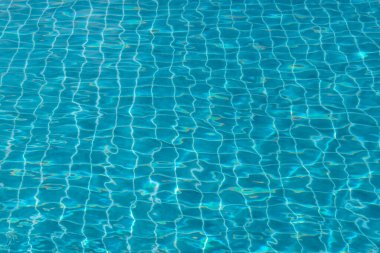 Su yüzeyinde dalga etkisi olan su yüzeyi havuzun dibindeki mavi kare fayansları görebilirsiniz. Yüzme havuzunda güneş yansımalı dalgalı mavi su